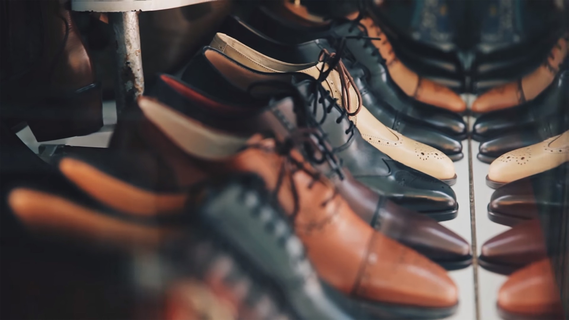 A number of pairs of formal men's shoes in different colors lined up in a row.